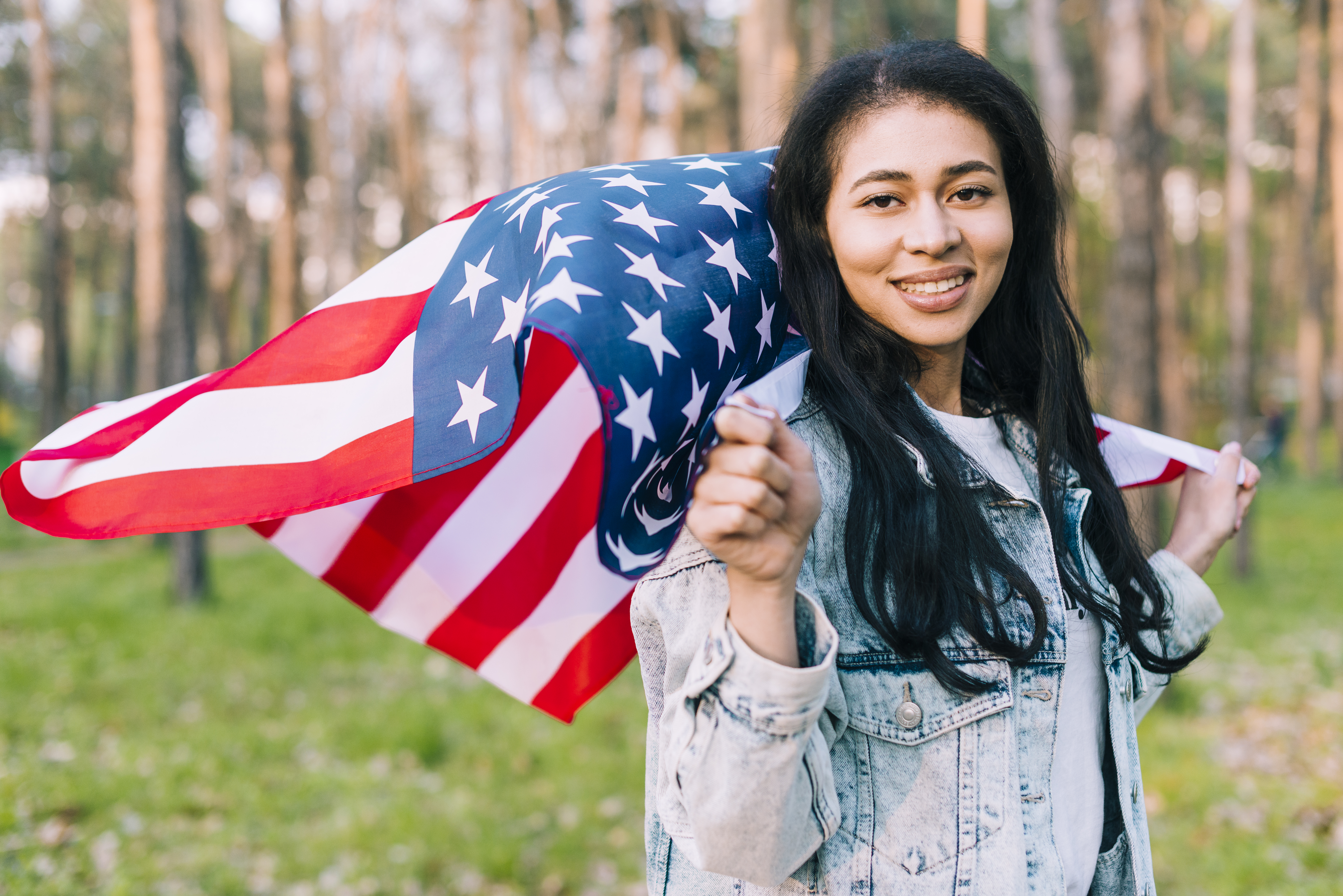 Smiling young female holding flying USA flag