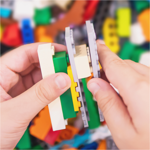 Photograph of a white child's hand holding lego pieces