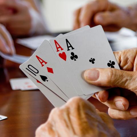 hand holds playing cards (ten and three aces)