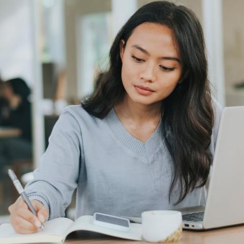 woman holding pen looks thoughtfully at notebook