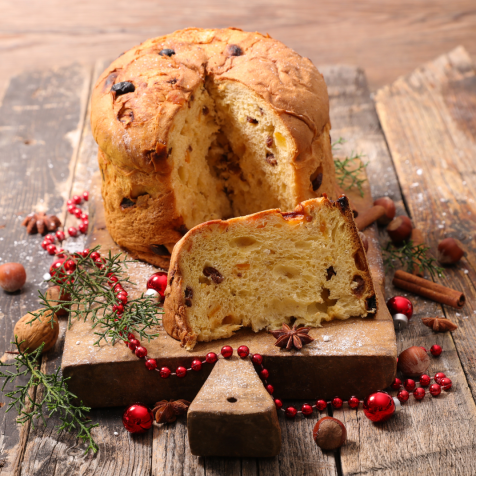 A festive holiday cake on a cutting board surrounded by evergreens, cranberries, and spices.