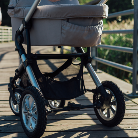 Photograph of a grey stroller on a boardwalk with a field in the background