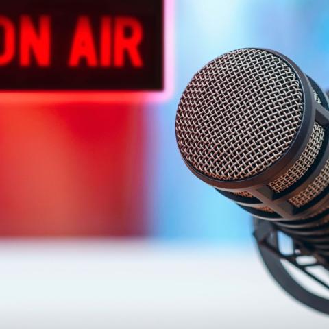 tabletop microphone with "on air" sign in background