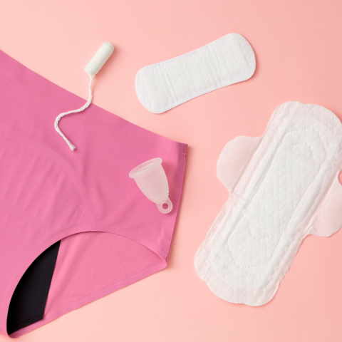 Menstrual products laid out over a pink background