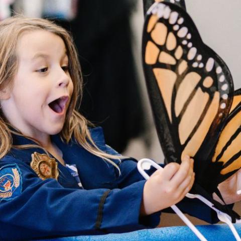 happy girl in police costume holds costume butterfly wings