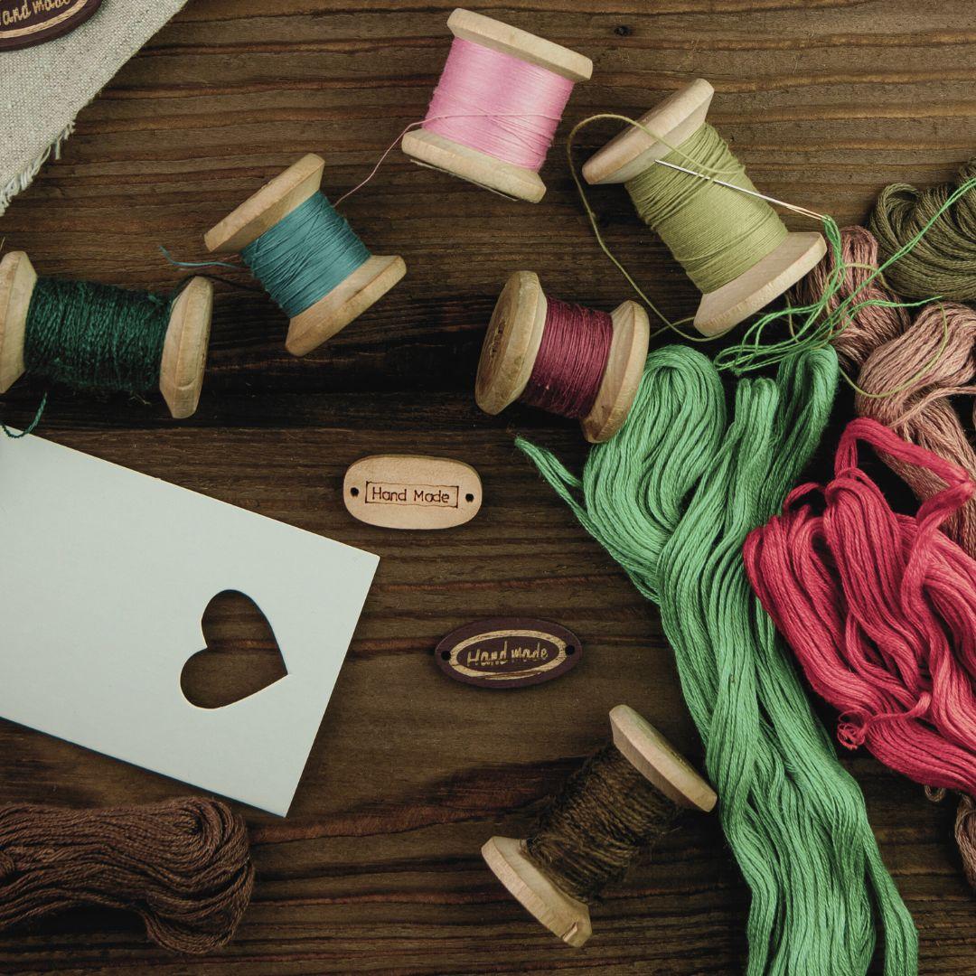 thread and embroidery floss on wood table with heart-punched card