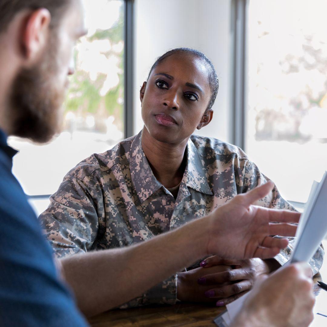 woman in soldier uniform talks business to man in blue shirt