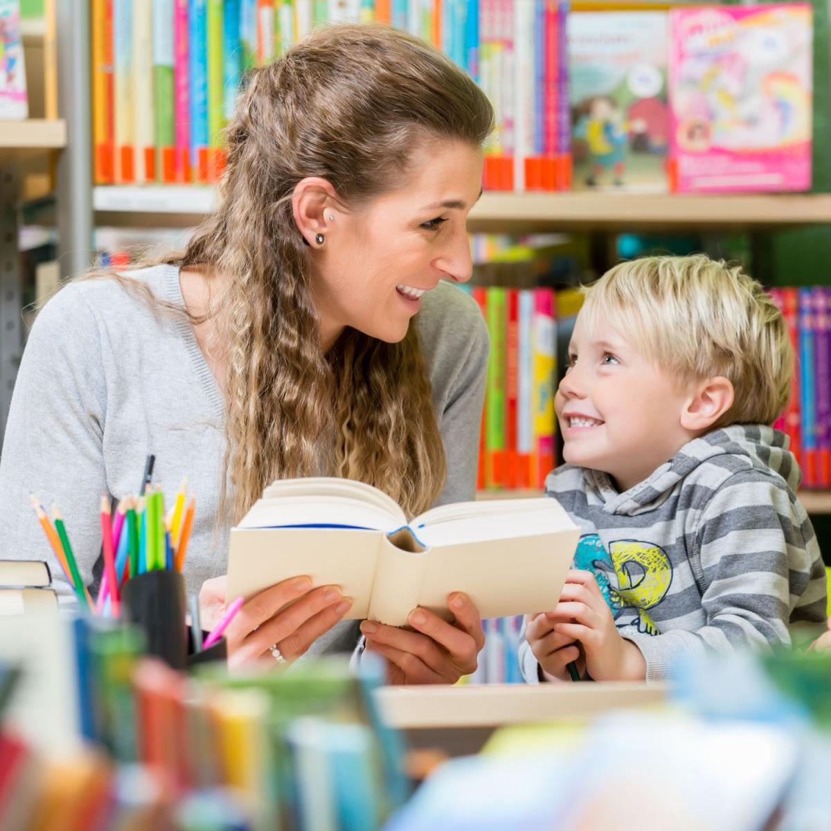 adult reads to child with art supplies in foreground