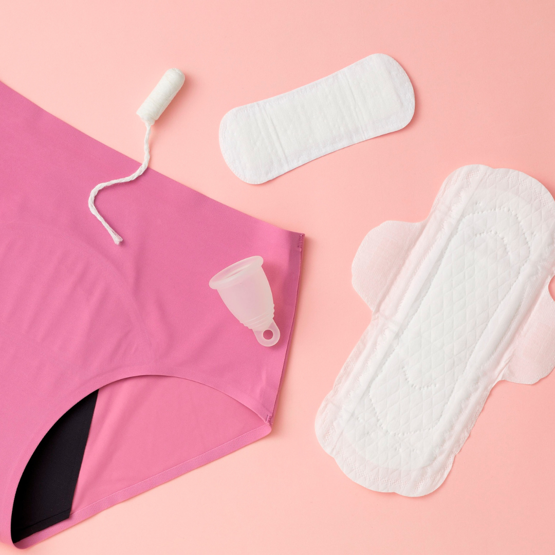 Menstrual products laid out over a pink background