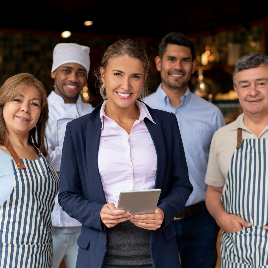 business person with tablet and happy kitchen staff behind them