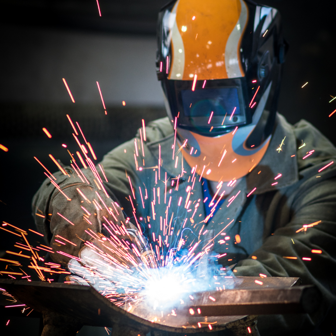 A person welding with sparks flying around their mask