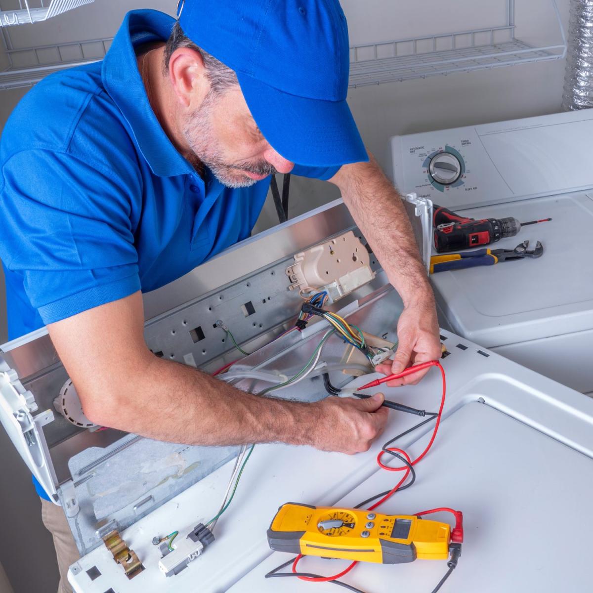 repair tech works on exposed wiring in washing machine