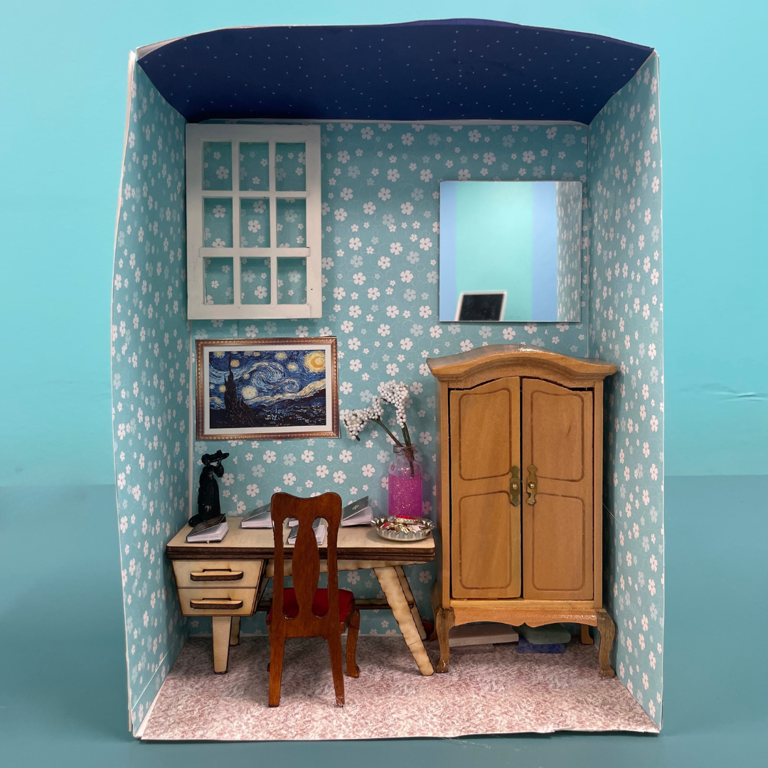 A cardboard box that has been decorated with dollhouse furniture to create a book nook. 